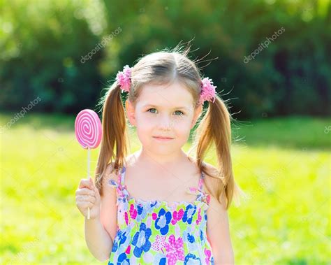 schattig meisje met twee blonde extensie met witte en roze lolly in haar hand buiten zomer