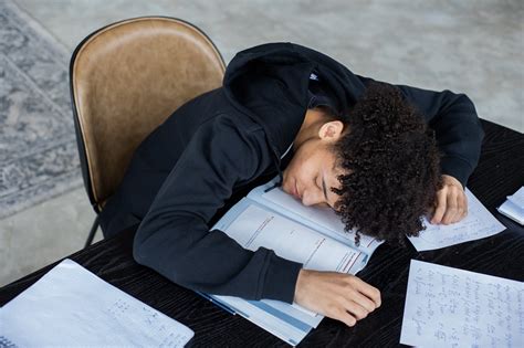 tired black man lying  opened book  homework papers  stock photo