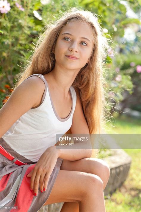 Beautiful Female Teenager Sitting Outdoors On Curbs Posing