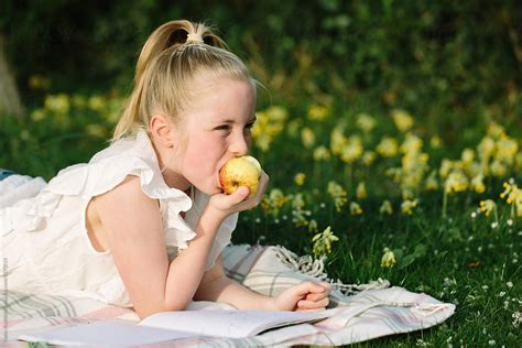 pretty tween girl eating an apple outdoors by stocksy contributor