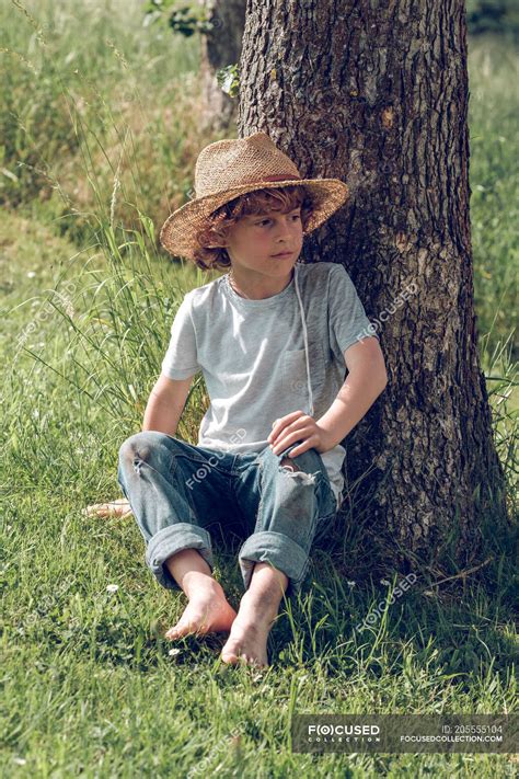 barefoot boy sitting  tree relaxing summertime stock photo
