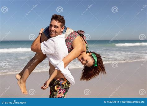 Man Carrying Woman On Shoulders On Beach In The Sunshine Stock Image