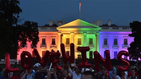 people hold balloon letters reading love wins in front of the white