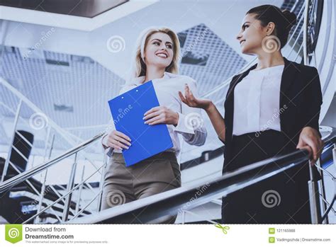 two attractive businesswomen standing on stairs stock
