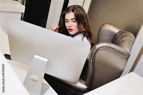 cute girl in a white shirt is sitting at the computer monitor office