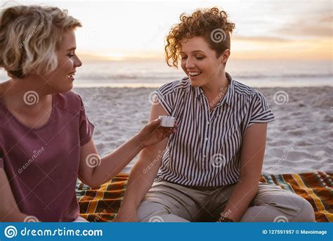 Young Lesbian Couple Sitting On A Beach Blanket At Dusk Stock Image