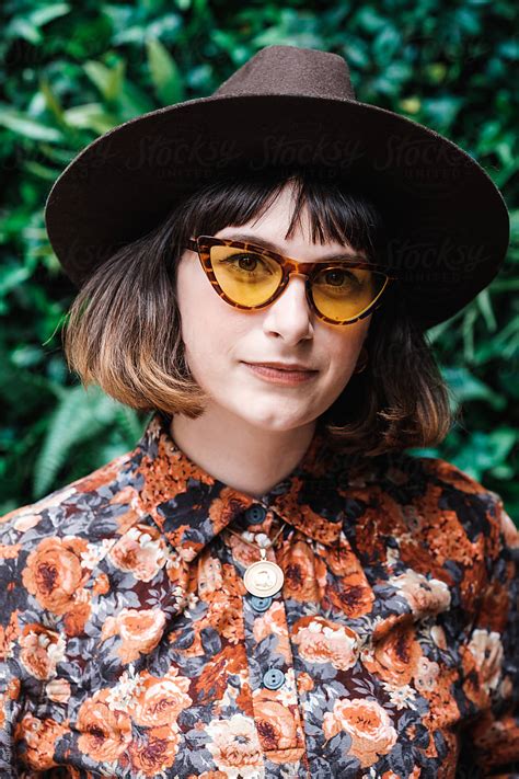 stylish woman wearing floral outfit and sunglasses looking at camera