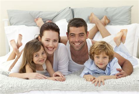 happy family lying  bed  smiling   camera womanstyle