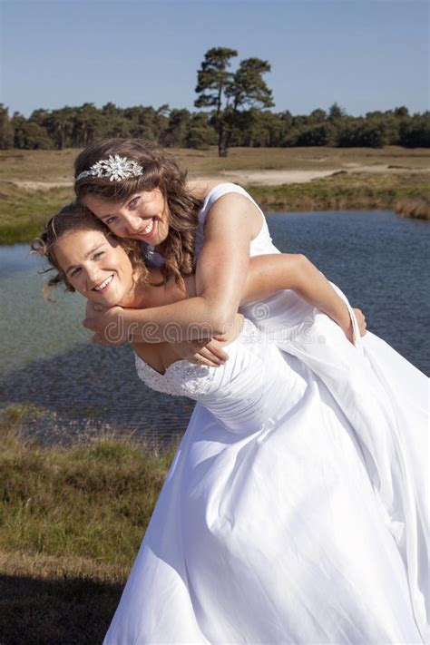 just married happy lesbian couple in white dress near small lake stock
