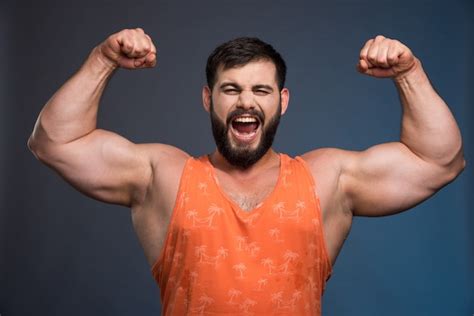 photo sportsman showing  muscles  dark blue wall