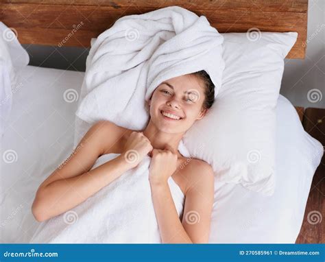 Woman Lying On Bed After Shower With Wet Hair With Towel On Her Head In
