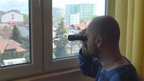 stalking people from window man using binoculars and having phone conversation stock footage