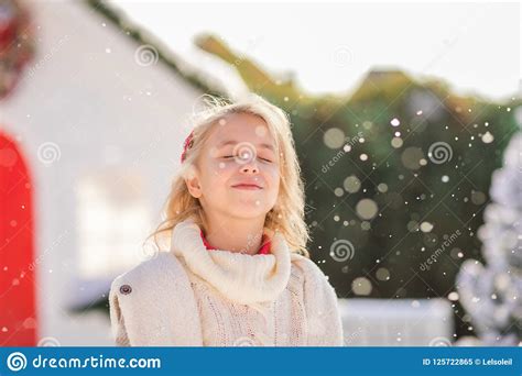 cute blonde girl near the small house and snow covered trees new year