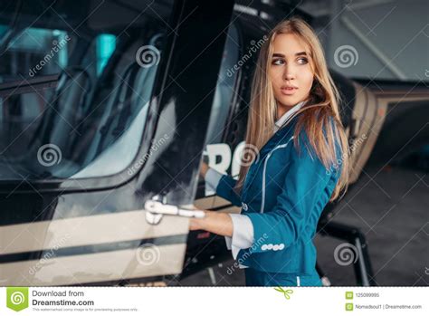 Female Flight Attendant Poses Against Helicopter Stock