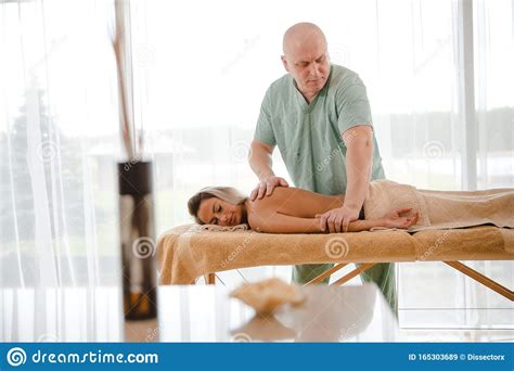 blonde woman relaxing receiving back massage from male physiotherapist