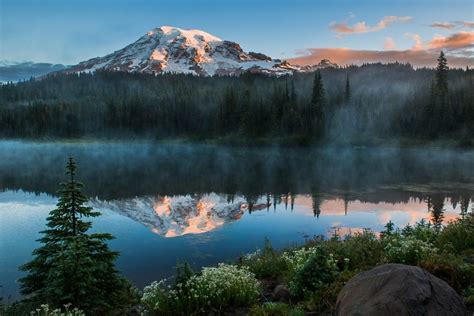 mountain  covered  mist   sits    body  water