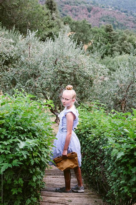female preteen girl walking through a garden to pick fruit by