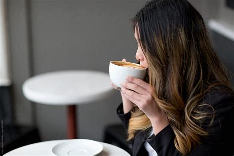 side view of asian woman drinking coffee stocksy united