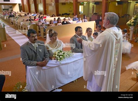 catholic priest administers wedding vows to two latino american couples