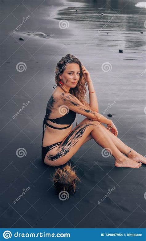 beautiful woman posing on the black sand beach in bali