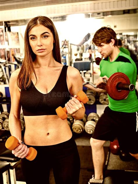 Sport Girl In Red Holding Dumbbells In Sport Gym Biceps In Foreground
