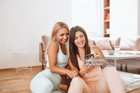 smiling lesbian females looking at selfies of themselves while sitting