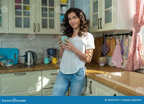 Brunette Woman Housewife In White T Shirt And Jeans At Home In The