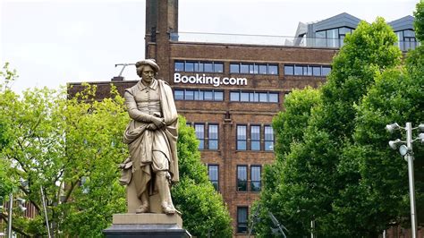 statue  man holding book  brown concrete building  daytime photo  booking