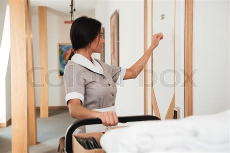 hotel maid knocking on the hotel room door for room service holding housekeeping cart stock