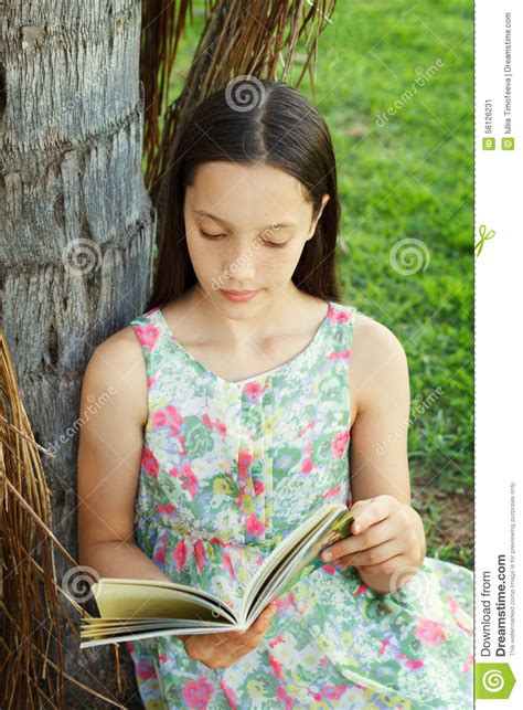 Cute Teen Girl Reading Book Sitting On Green Grass Stock