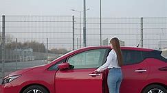 Attractive female using modern technology to unlock car doors. Woman pening door and getting in car. A girl opens the car and sits inside.