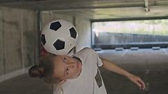 Teenager girl football soccer player practicing tricks, kicks and moves with ball inside empty covered parking garage. Urban city lifestyle outdoors concepte. 4K UHD slow motion RAW graded footage