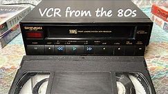 Hand Takes a Tape and inserts it into a VCR — VHS device-VCR from the 80s