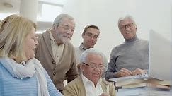 Group of senior people with teacher looking at laptop screen. Medium shot of elderly men and woman having class in library, talking, studying together on weekend. Education, retirement concept