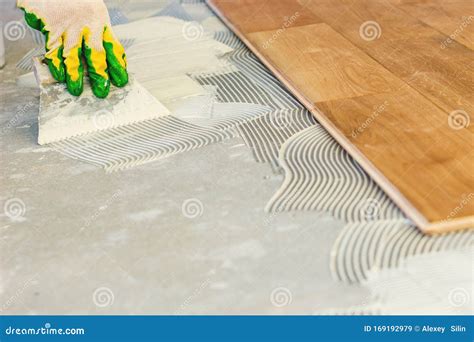 The Master Smears the Glue on the Concrete Floor and Lays the Parquet ...