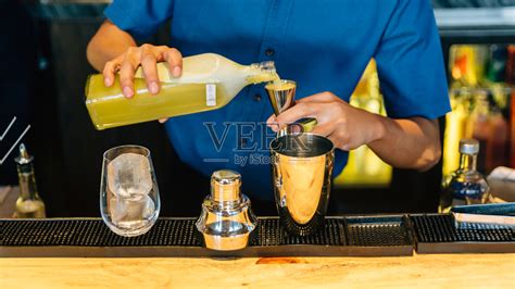 调酒师制作鸡尾酒与摇壶，两倍大小的Jiggers和饮杯与冰块在鸡尾酒柜台酒吧。照片摄影图片_ID:330597996-Veer图库