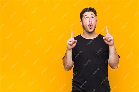 Premium Photo | Young man feeling awed and open mouthed pointing ...