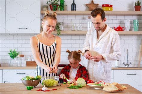 Picture of parents with daughter cooking food in kitchen | People ...