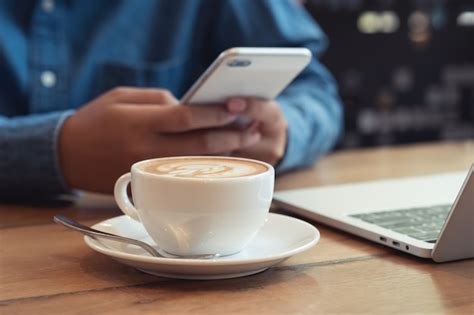 Close up white coffee cup with latte art on wood table. businessman ...