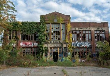 An old abandoned school building with overgrown vegetation shattered ...