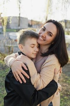 Young beautiful woman hugs her little son a walk in the spring park ...