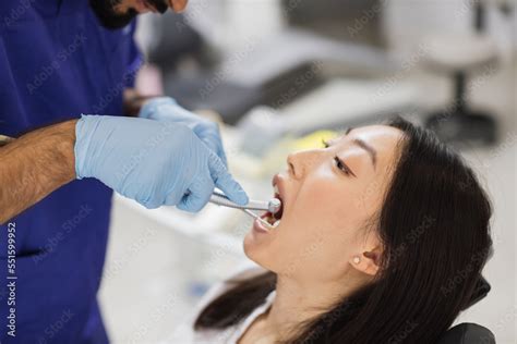 Dentist carrying out dental procedure on male patient, close-up