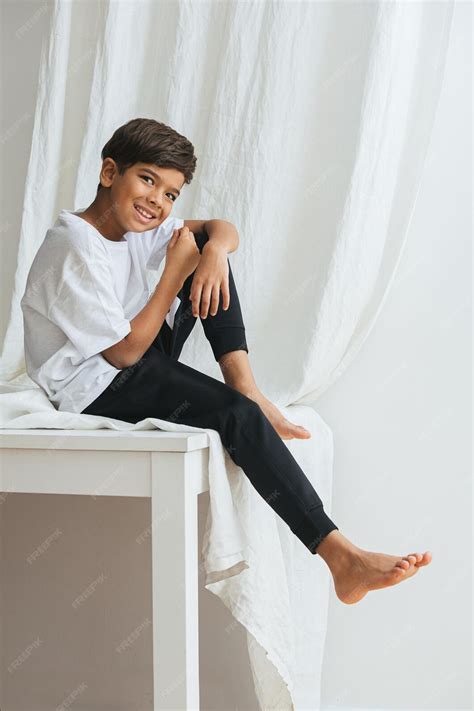 Premium Photo | Happy indian boy sitting on a table awkwardly smiling ...