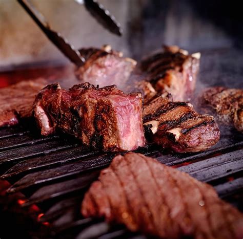 A person grilling meat on a grill | Premium Photo
