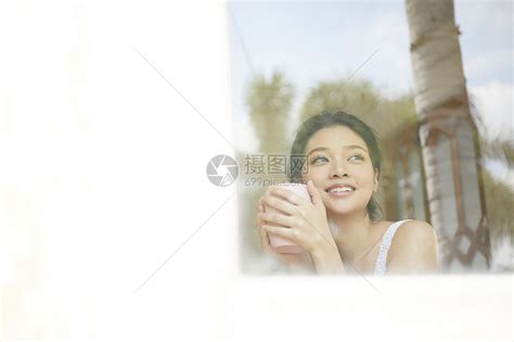 捧着杯子看向窗外的年轻女子高清图片下载-正版图片502244634-摄图网