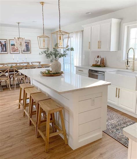a kitchen with white cabinets and wooden stools next to an island in ...