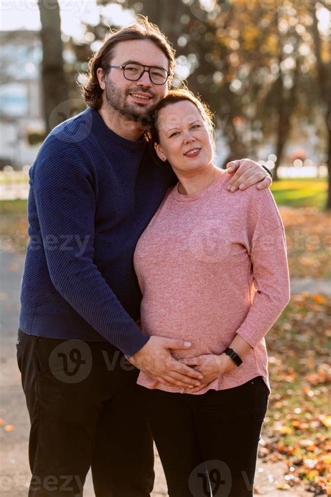 un hombre cariñosamente abraza su embarazada esposa en el parque ...