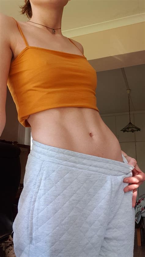 Belly stretching in pink crop top and blue jeans showing a toned ...