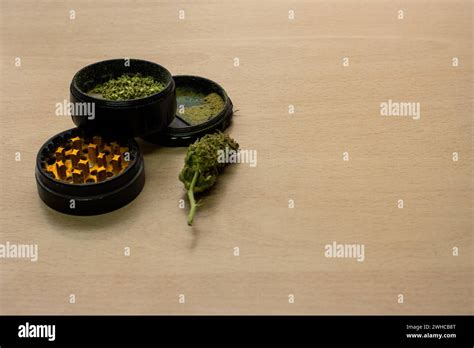 A grinder for pressing marijuana with a bud next to it on a wooden ...