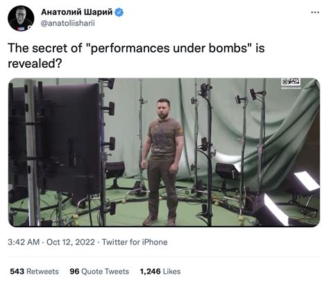 Zelensky wearing a green shirt speaks in a dimly-lit room. An out-of-focus Christmas tree is in the
